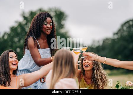 Groupe joyeux d'amis divers trinquant en plein air Banque D'Images