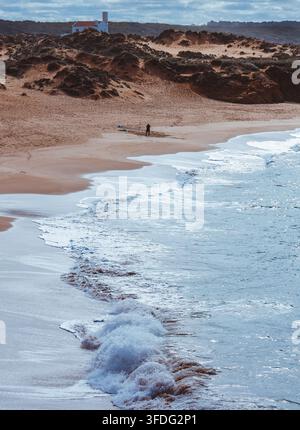 Une personne seule pêchant sur une plage de sable isolée Banque D'Images