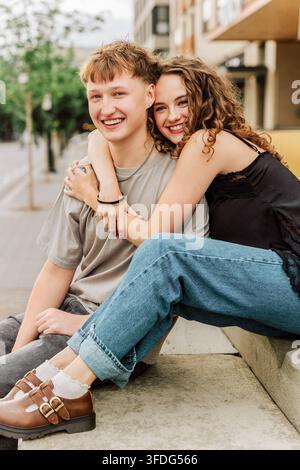 Jeun couple heureux enlacé sur les marches de la ville Banque D'Images