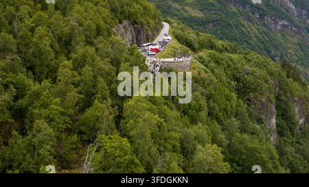 Perspective aérienne d'une route de montagne sinueuse avec zone de stationnement en retrait nichée parmi une forêt de conifères dense sur un terrain de pente raide. Banque D'Images