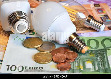 Ampoules LED modernes et pièces sur des billets en euros, concept de comparaison d'efficacité énergétique et de coût électrique Banque D'Images