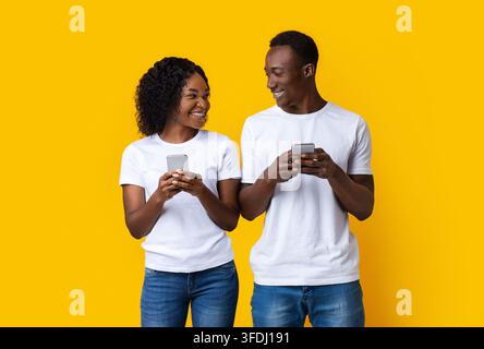 Jeune homme souriant et jeune femme jouant ensemble sur les smartphones Banque D'Images
