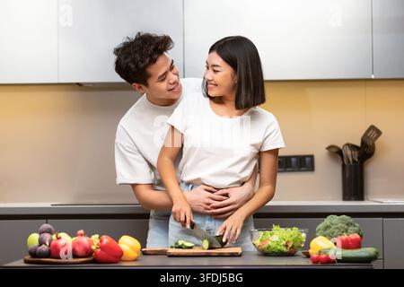 Joyeux couple chinois cuisine préparation du dîner ensemble debout dans la cuisine Banque D'Images