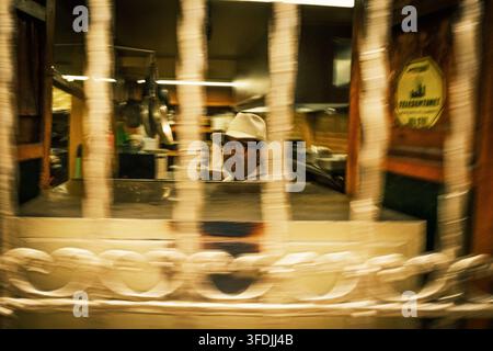 Bogota, Bogota, Colombie – 17 juin 2023 : Vue d'un homme portant un chapeau et des lunettes dans une cuisine, vu à travers une grille décorative en métal. Banque D'Images