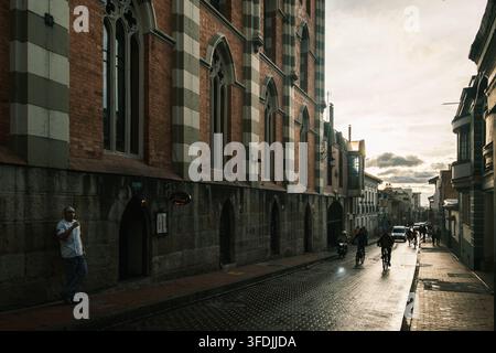 Bogota, Colombie - 17 juin 2023 : Vue d'un bâtiment historique en briques avec des arches gothiques le long d'une rue étroite, avec un homme debout sur le trottoir et c Banque D'Images