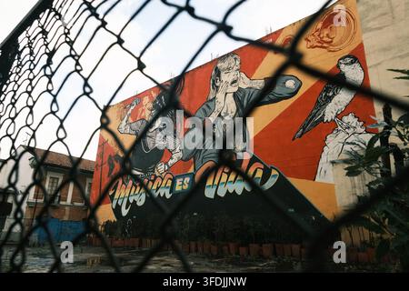 Bogota, Colombie – 17 juin 2023 : Vue d'une fresque d'art de rue vibrante représentant une femme chantant et un oiseau, vue à travers une clôture en grillage dans un urba Banque D'Images
