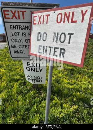 Plusieurs panneaux „Sortie uniquement“ et „Interdiction d'entrée“ qui se chevauchent à l'entrée et à la sortie d'un parking. Banque D'Images