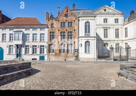 La ville de Bruges en Belgique, Europe. Des lignes d'architecture européenne historique bordent une place pavée sous un ciel bleu clair, mettant en valeur le charme et le style du monde ancien Banque D'Images