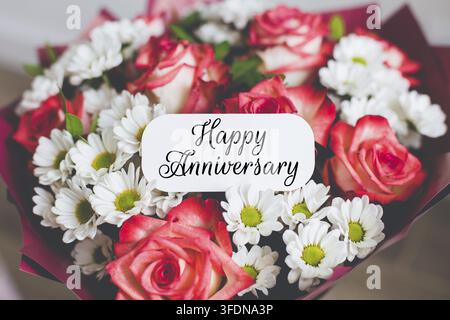 Magnifique bouquet de roses roses et de marguerites blanches avec une carte portant l'inscription "Joyeux Anniversaire", concept d'amour, de célébration, de romance et d'appréciation en Banque D'Images