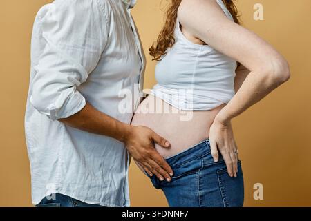 Couple enceinte embrassant le ventre enceinte lors d'une séance photo maternité intime avec des touches d'amour Banque D'Images