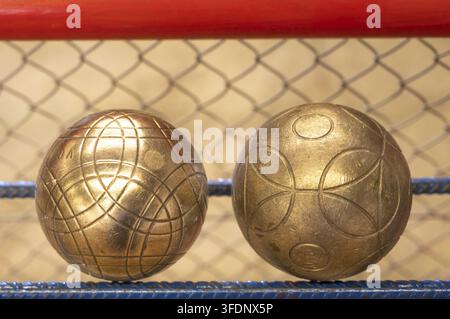 Deux boules en laiton gravées pour le jeu traditionnel de boule lyonnaise, une variante du jeu de boules avec des boules plus grandes et plus lourdes, reposent en gros plan sur une ga Banque D'Images