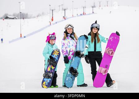 Famille avec enfants profitant du snowboard sur une pente de station de ski. Sports d'hiver et amusement en plein air Banque D'Images