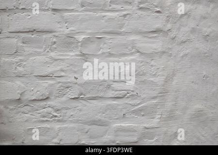 Vue rapprochée d'un mur de briques blanchi avec une peinture inégale révélant la maçonnerie et une subtile altération créant un fond texturé neutre dans le Brug historique Banque D'Images