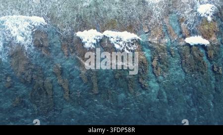 Les vagues de l'océan se brisent sur un magnifique récif corallien peu profond créant des motifs naturels dans l'eau turquoise Banque D'Images