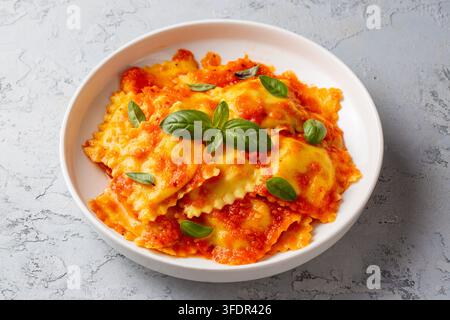 Raviolis italiens faits maison avec sauce tomate et feuilles de basilic frais sur une assiette blanche Banque D'Images