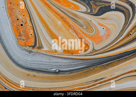 gros plan d'un fond de peinture fluide présentant des tourbillons de marbre orange, gris et crème avec des bulles Banque D'Images