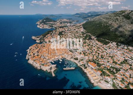 Une photographie aérienne époustouflante de la vieille ville de Dubrovnik en Croatie, mettant en valeur ses murs de ville médiévaux emblématiques, ses toits en terre cuite et les eaux bleues vives de la mer Adriatique. L'image capture le port historique, les collines environnantes et le vert luxuriant de la Banque D'Images