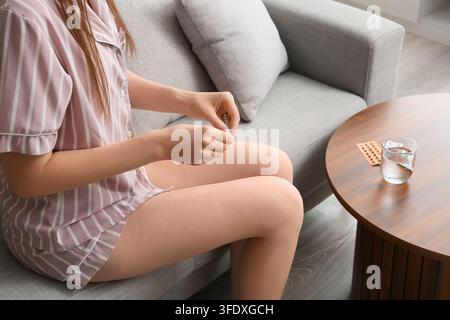 Contrôle des naissances et santé reproductive, femme prenant quotidiennement une pilule contraceptive à la maison pour la planification familiale et la prévention de la grossesse dans le salon Banque D'Images