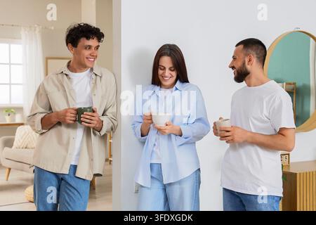 Collaboration au travail et connexion sociale, jeunes collègues divers discutant et buvant du café pendant une pause dans un intérieur de bureau moderne et lumineux Banque D'Images