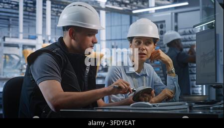 Ingénieur masculin et féminin inspectant une pièce métallique avec un étrier tout en discutant des données CAO. L'assurance qualité collaborative et le dépannage optimisent les lignes de production automatisées modernes. Travail d'équipe. Banque D'Images