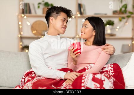 Un couple coréen amoureux se fait un plaisir de boire un café chaud à l'intérieur Banque D'Images