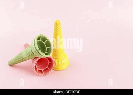 Gaufres croustillantes en cornettes de glace multicolores sur fond rose, espace de copie Banque D'Images