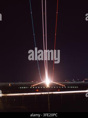 Exposition longue dramatique montrant les traînées de lumière colorées d'un avion au décollage sur la piste éclairée de l'aéroport de Lanzarote, en Espagne. Banque D'Images