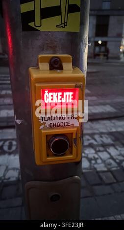 Bouton de signalisation piétonne jaune avec panneau d'attente rouge lumineux sur le poteau de rue Banque D'Images
