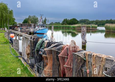 Filets Fyke séchant et bateau de pêche amarré dans le vieux port de Gothmund, village de pêcheurs sur la rivière Trave, Schleswig-Holstein, Allemagne Banque D'Images