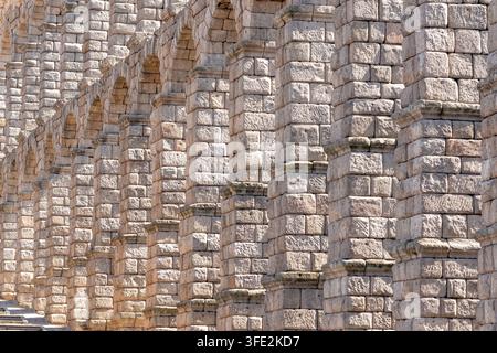 Les arches massives en pierre de l'aqueduc romain de Ségovie, en Espagne, révèlent une maçonnerie texturée, un rythme répétitif et des détails d'ingénierie classiques, transmettant un sentiment Banque D'Images