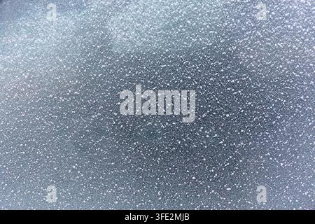 La transformation glaciale du verre transforme une vitre automobile en un champ de fins cristaux de glace blancs et de formes réfléchies sombres, créant un hiver abstrait Banque D'Images