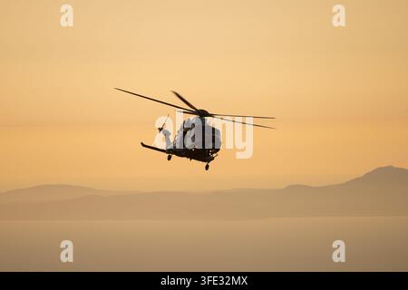 L'hélicoptère SAR AW189 des garde-côtes britanniques s'incline dans la lumière dorée du soir au-dessus des montagnes d'Eryri lors d'une mission de sauvetage Cadair Idris au Pays de Galles. Banque D'Images