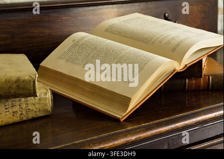 Livre ancien ouvert avec des pages vieillies reposant sur de vieux livres reliés en cuir sur une table en bois, nature morte littéraire traditionnelle Banque D'Images