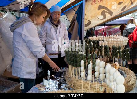 Le dango (boules de riz mochi sur brochettes) rôti sur un feu de charbon de bois pour une délicieuse friandise fait une collation japonaise populaire pendant les mois froids d'hiver. Banque D'Images