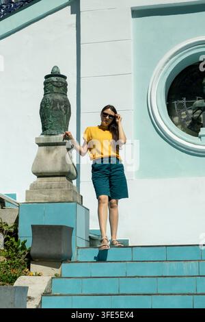 Jeune femme debout sur des marches ensoleillées à côté d'une architecture historique en été Banque D'Images