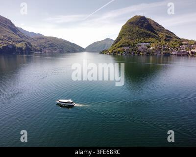 Vue aérienne d'un bateau de passagers naviguant sur le lac de Côme avec les pentes verdoyantes du Monte San Salvatore à Lugano, Tessin, Suisse. Banque D'Images