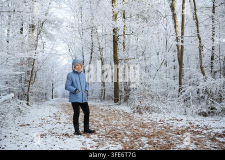 Femme debout sur un sentier forestier en hiver, réserve naturelle de Beversee, Bergkamen, Rhénanie-du-Nord-Westphalie, Allemagne Banque D'Images
