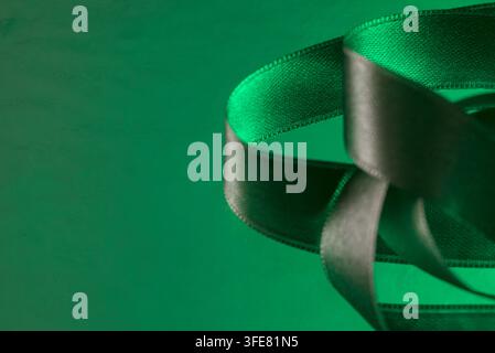 Des plis de ruban de satin vert vif présentent élégamment une texture lisse et brillante. Banque D'Images