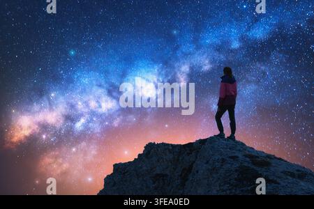 Voie lactée incandescente et femme sur le sommet de la montagne à la nuit étoilée Banque D'Images
