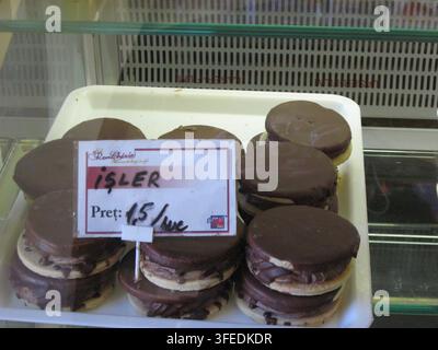 Sandwichs biscuits glacés au chocolat exposés sur un plateau dans une vitrine de boulangerie. Banque D'Images