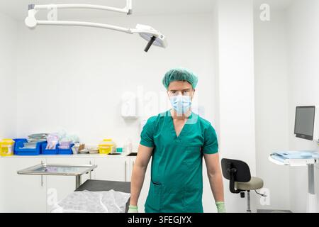 Chirurg portant une blouse, un filet à cheveux, un masque et des gants debout dans une salle d'opération Banque D'Images