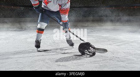 Patinoire de hockey sur glace avec un joueur professionnel tirant le palet avec une crosse de hockey. Banque D'Images