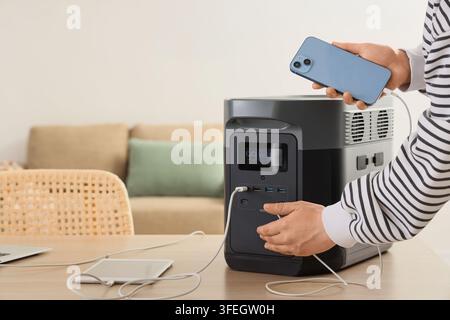 Indépendance énergétique et alimentation portable, personne chargeant un smartphone avec une station à haute capacité de batterie pour la sauvegarde en cas d'urgence et la vie hors réseau Banque D'Images