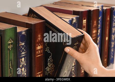 Éducation et connaissance, personne choisissant un livre vintage sur une étagère de bibliothèque pour la recherche et l'étude académique dans une librairie classique ou une bibliothèque à domicile Banque D'Images