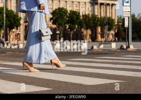 Réussite professionnelle et style de vie professionnel, femme en costume d'affaires marchant sur un passage piéton dans la ville avec un sac à main pour les trajets d'entreprise et la mobilité urbaine Banque D'Images