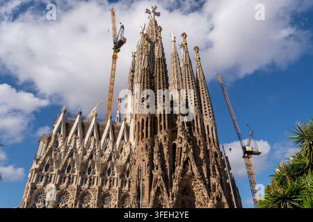 Barcelone, Espagne 31.08.2026 : le chantier de la Sagrada Familia s’élève sous un ciel bleu, avec de grandes grues à côté de flèches en pierre ornées et d’une façade inachevée. Banque D'Images