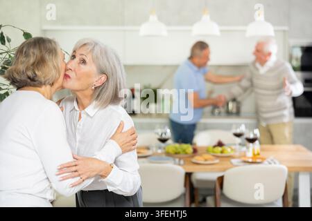 Deux amies âgées s'embrassant dans la cuisine à la maison Banque D'Images