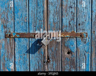 Porte en bois bleue patinée avec de la peinture écaillée et un cadenas en métal rouillé Banque D'Images