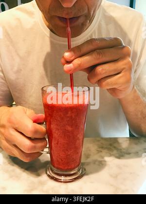 Homme buvant un smoothie aux baies. Banque D'Images