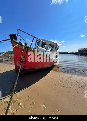 Un vieux bateau rouge échoué sur le sable du port de Youghal, comté de Cork, mer d’Irlande Banque D'Images